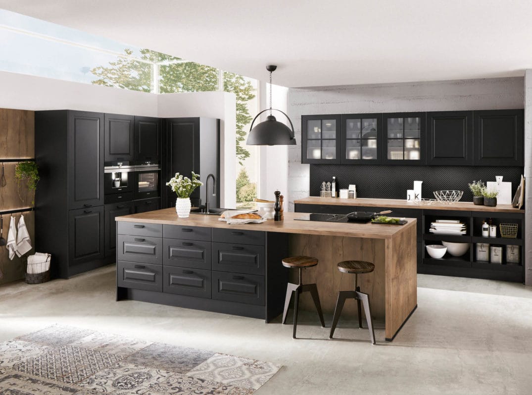 Image d'une cuisine de campagne noire avec un coin salon et un plan de travail en bois